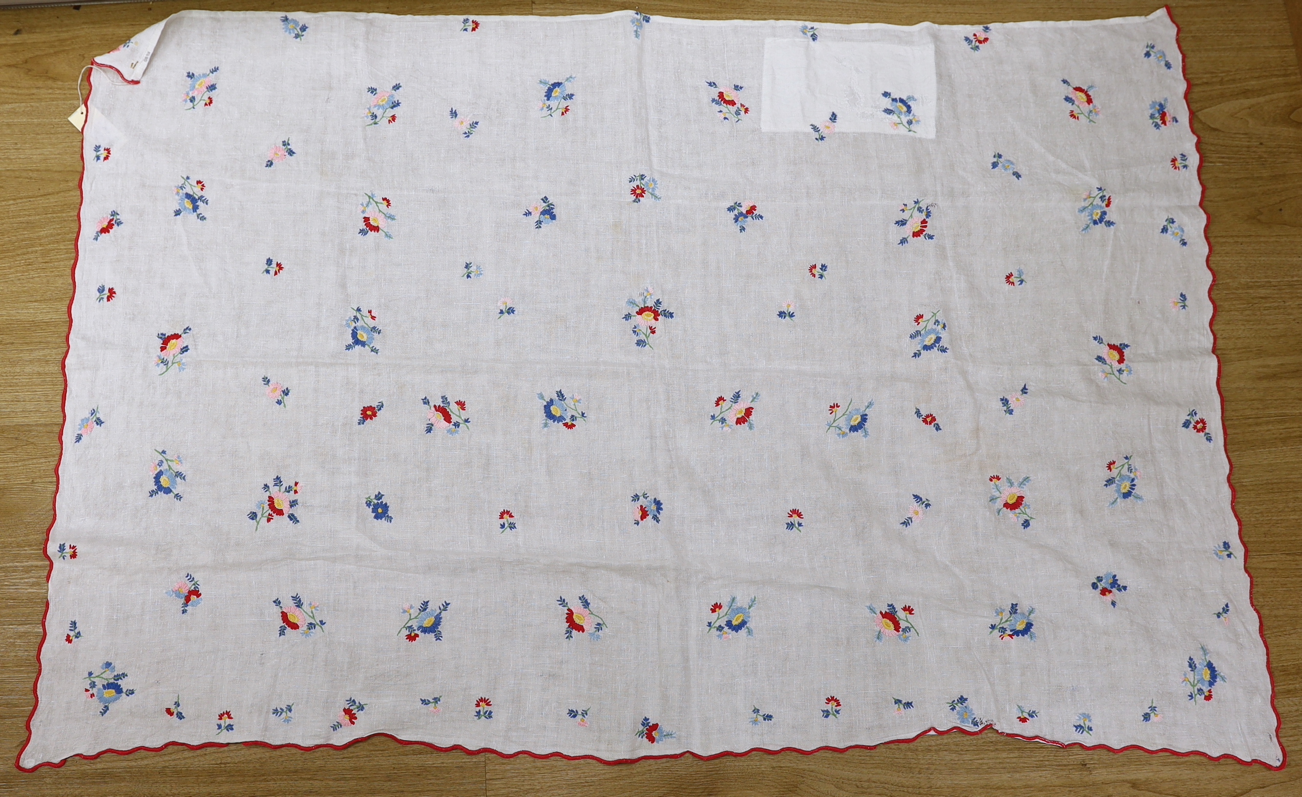 A 20th century woven linen panel, hand embroidered with scattered floral polychrome sprigs and a scalloped red buttonholed embroidered edge, possibly Swiss, 153 x 100cm